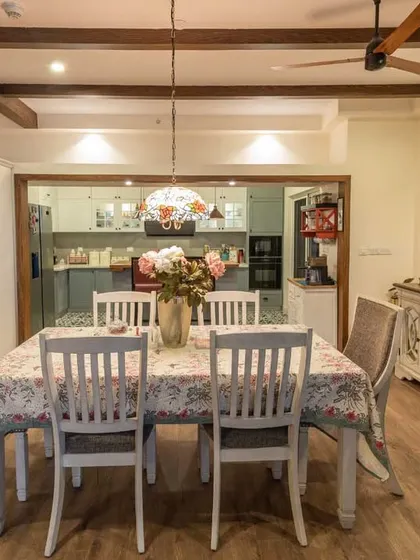 The dining area in our Brigade Exotica project, featuring a classic white table and chairs. The open layout provides a clear view into the modern island kitchen.