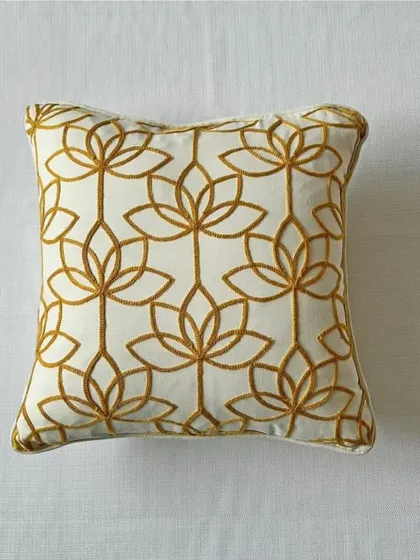 A clean, product-focused shot of our lotus embroidery cushion cover, highlighting the intricate golden thread work on the off-white fabric.
