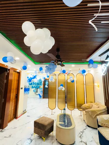 A modern home decorated for a 'Welcome Baby' celebration. The living room has balloon clusters on the ceiling and a backdrop in the background.