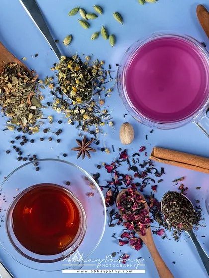 This vibrant flat lay shows both the loose tea leaves and the colorful brewed teas they produce. The composition is a celebration of color and flavor, perfect for a premium tea brand.