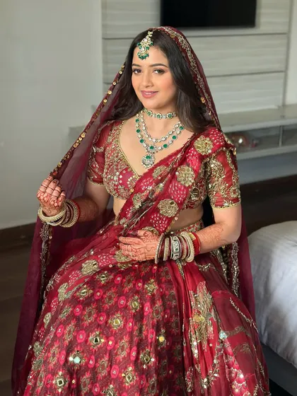 The complete look, with her dupatta set. The soft glam makeup perfectly complements the intricate jewelry and the rich color of her red bridal lehenga.
