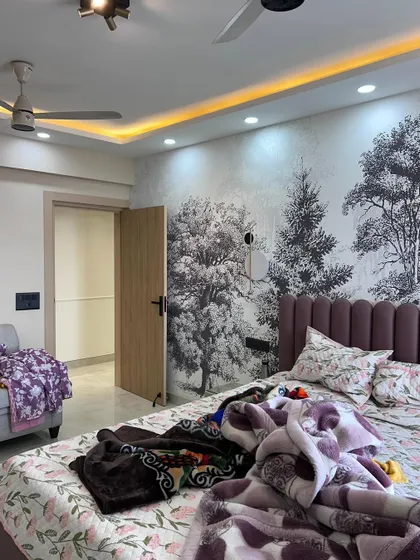 Another angle of the bedroom with the forest mural, showing the false ceiling with cove lighting that enhances the room's atmosphere.