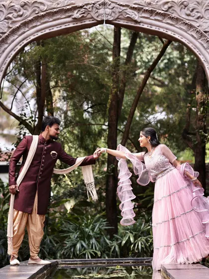 A fairytale moment captured perfectly. The groom-to-be is in a handsome maroon sherwani, while she wears a delicate pink tiered lehenga, creating a beautiful contrast.