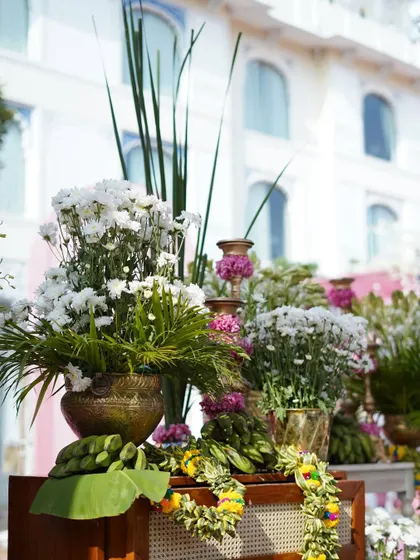 A detail of the floral arrangements used throughout the venue, featuring a mix of white chrysanthemums and other seasonal flowers in traditional brass pots, accented with banana leaves.