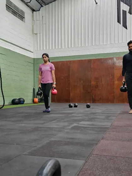 Three members performing kettlebell carries. This simple but effective exercise prepares your body for real-world tasks like carrying groceries or luggage.
