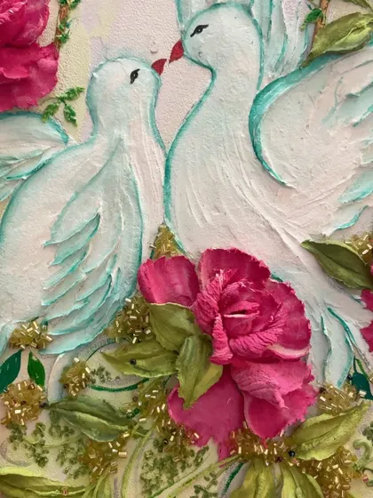A close-up of a magnificent wall art piece with two sculpted white pigeons kissing amidst a garden of deep pink roses.