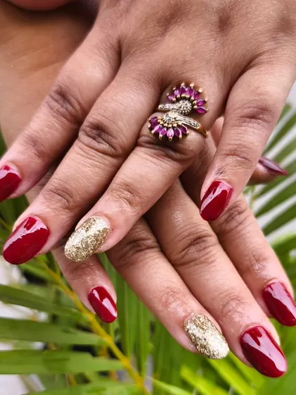 Classic party nails featuring temporary extensions with a deep red polish and a full gold glitter accent nail for a touch of glam.