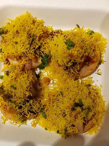 A close up of my freshly prepared Sev Puri. Each bite is a burst of flavor, made with crisp puris, tangy chutneys, and a generous topping of sev. It's a perfect example of the authentic Mumbai street food I can bring to your gathering.