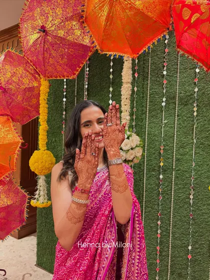 The beautiful 24-hour henna stain on my bride, perfectly complementing her pink bandhani saree. Seeing my clients this happy is the best reward.