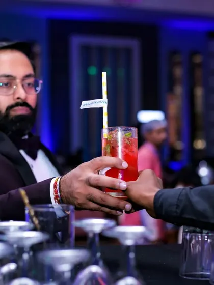 A guest receives a vibrant red cocktail from one of my bartenders. The focus is on the seamless and friendly service experience at the bar.