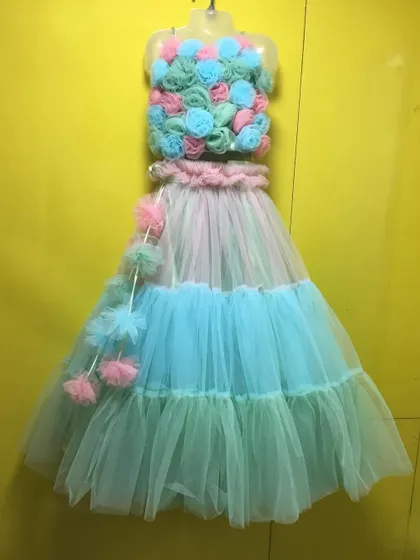 A unique crop top and skirt set with a bodice made of fabric flowers and a tiered pastel skirt.