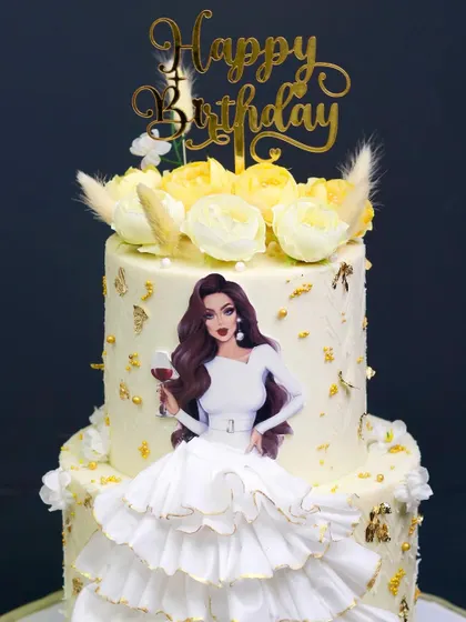 Cakes define your love in the form of edible art. This two-tiered white cake features a 3D ruffled skirt and a stylish topper for a special birthday.