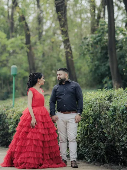 A candid moment within a cinematic shoot. As the couple walks hand-in-hand through a park path in Pune, her magnificent red dress adds a touch of drama to this otherwise natural interaction, blending two styles perfectly.