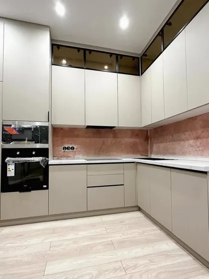 Another angle of the Palam Vihar kitchen, highlighting the seamless look of the handle-less cabinetry and the warm glow from the under-cabinet lighting against the unique backsplash.