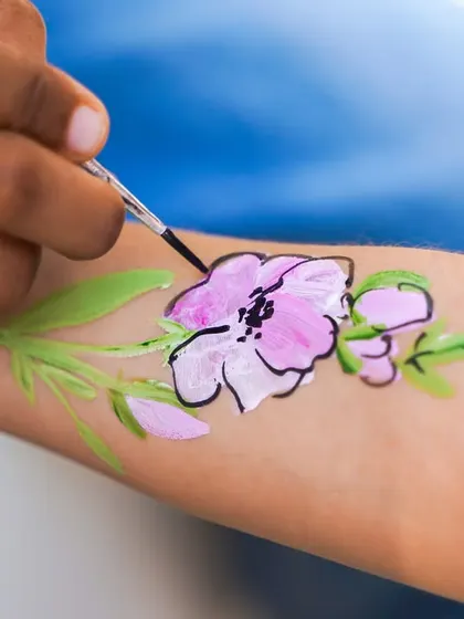Our talented artist painting a delicate and beautiful flower design on a guest's arm at our temporary tattoo station.