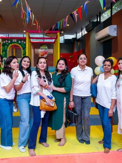 A group of moms posing for a photo, relaxed and happy while their kids play safely nearby. I aim to create a comfortable environment for parents too.