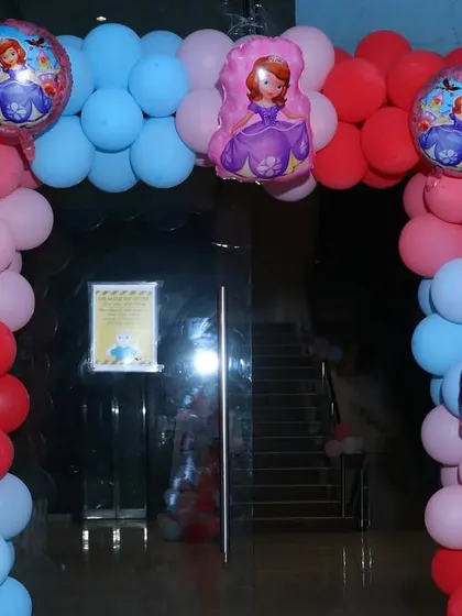 A princess-themed balloon arch at the entrance of a party. The arch is decorated in red, pink, and blue with princess foil balloons.