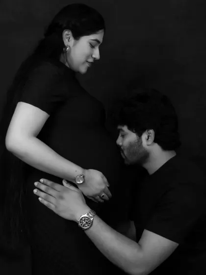 A classic and tender black and white portrait. The father-to-be gently kisses the baby bump, a timeless expression of love and anticipation for their little one.