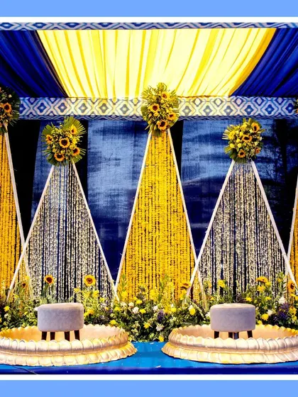 The Haldi ceremony stage, featuring a backdrop of blue and yellow drapes with hanging floral strings. The setup is both traditional and visually striking, perfect for the main ritual.