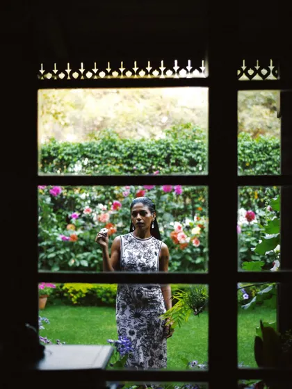 Anasuya Sengupta framed by a window, looking out onto a garden. This shot creates a sense of story and introspection, as if we are peeking into a private moment.