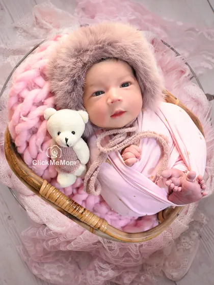 Here is the same baby girl, now awake and curious, wearing an adorable furry hood and posing with her teddy bear companion.