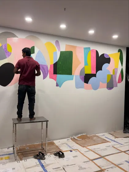 My team member working on the large-scale abstract mural for a commercial space. This image shows the physical effort and scale involved in bringing a 42-foot artwork to life.