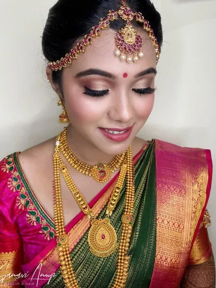 This bride's look features a soft brown smokey eye and a neutral lip, a beautiful combination that complements her green and pink saree.