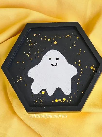 This hexagonal trinket tray features a sparkly ghost against a black background with gold flecks. It's a practical way to keep small items organized while being festive.