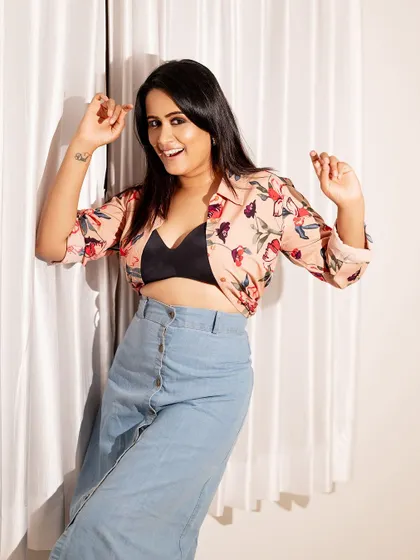 A fun and casual studio portrait. The floral shirt and denim skirt create a playful, summery vibe, and the expression is full of life.