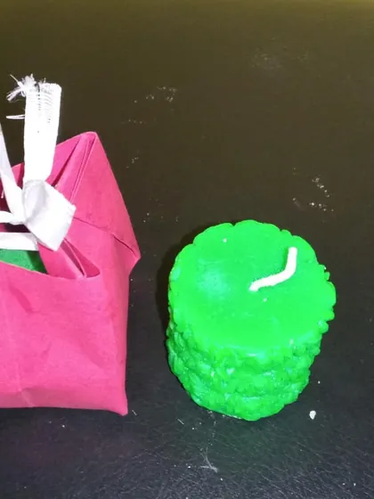This view shows the decorative candle being placed inside its gift bag, ready to be given as a special, handmade gift.
