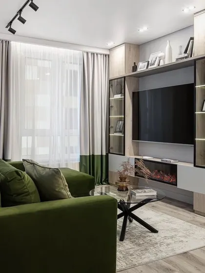 This living room TV unit combines light wood tones with glass-fronted display cabinets and an integrated electric fireplace, creating a cozy and modern entertainment center.