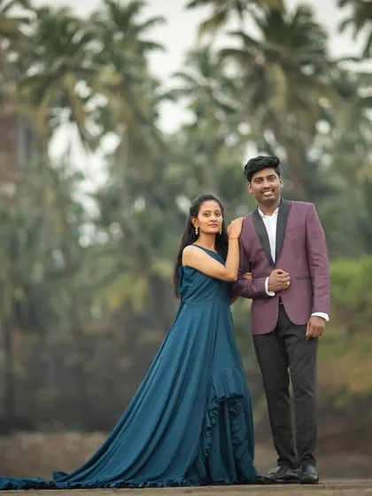 A stylish couple portrait in front of the iconic palm trees and fort ruins at Alibaug beach, blending glamour with a rustic setting.