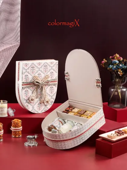 This uniquely shaped oval box is a statement piece in our collection. The intricate pattern and elaborate bow make it a luxurious choice for gifting, filled with premium sweets and savories.