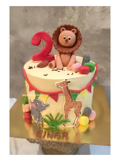 A cute jungle theme cake for a second birthday. This design features hand modeled fondant animals, including a lion, elephant, and giraffe, on a cheerful yellow cake.
