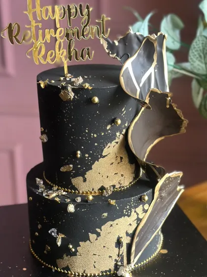 Bold, beautiful, and dipped in gold. This black and gold two-tiered cake, designed for a retirement party, makes a luxurious statement with its abstract sails and gold splatter.