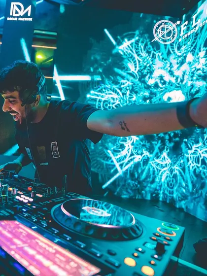 Reaching out to the crowd from the DJ booth against a stunning blue visual backdrop. It's all about connection.