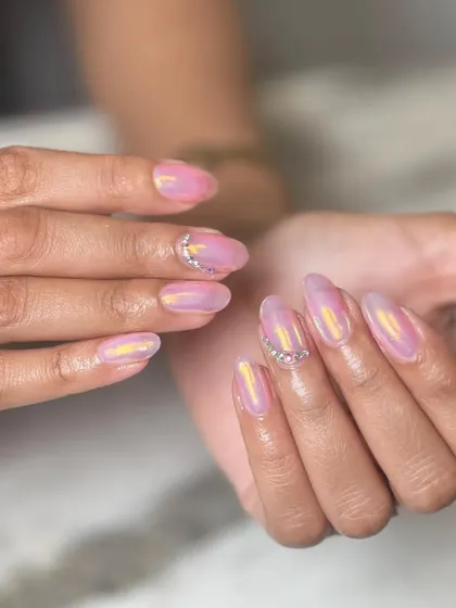 A beautiful iridescent pink chrome manicure with a delicate rhinestone accent at the cuticle. It's a simple way to add a touch of glam to a trendy finish.