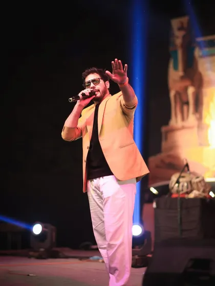 A full-length shot on the beautifully lit stage of the Winter Souk. My presence is professional yet approachable, perfect for a community gathering.
