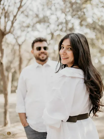 A playful shot with the woman in focus, smiling back at her partner who is blurred in the background. This composition creates depth and tells a story of their interaction.
