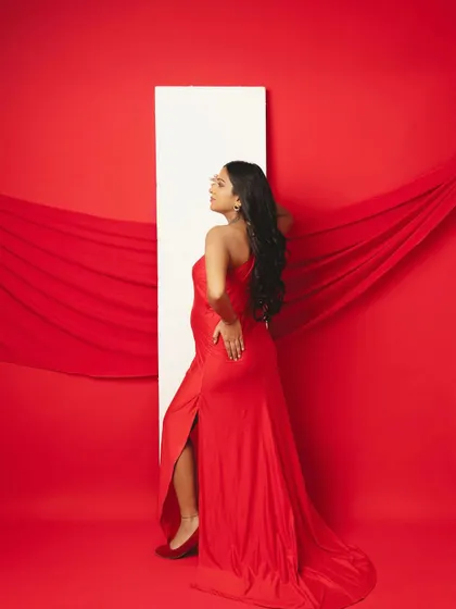 Bold and confident. The striking red background and the sleek red dress create a powerful, high-fashion maternity portrait.