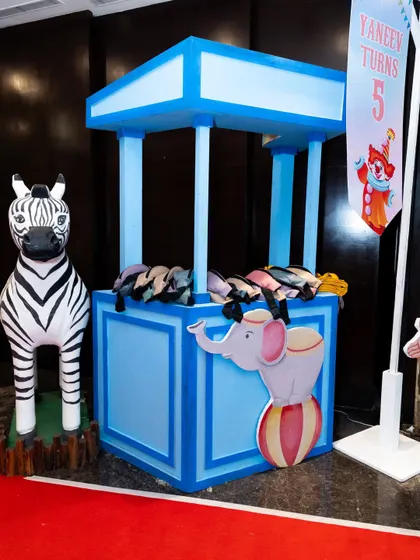 A charming blue carnival booth, decorated with an elephant and zebra prop, ready to host a fun game or activity.