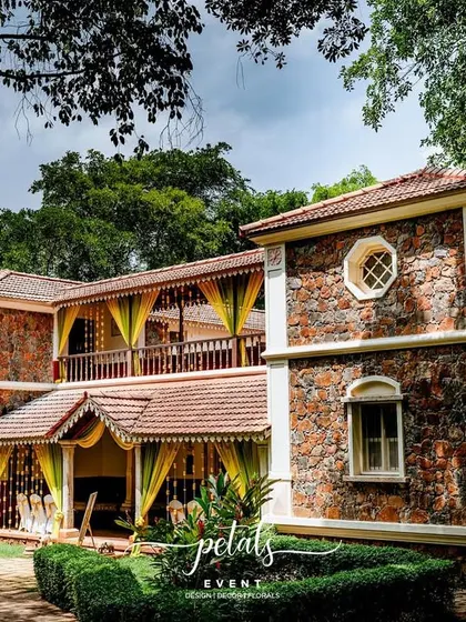 The beautiful heritage building of Angana, The Courtyard, draped in yellow fabric and marigolds for a Haldi ceremony. The decor complements the rustic stone walls and tiled roof perfectly.