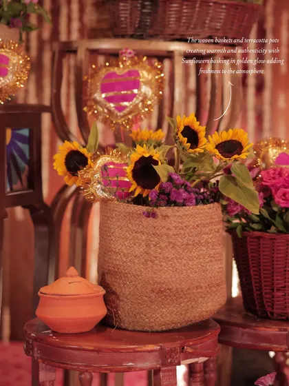 A detail shot showing sunflowers in a jute basket next to a terracotta pot, highlighting the warm and authentic textures of the decor.