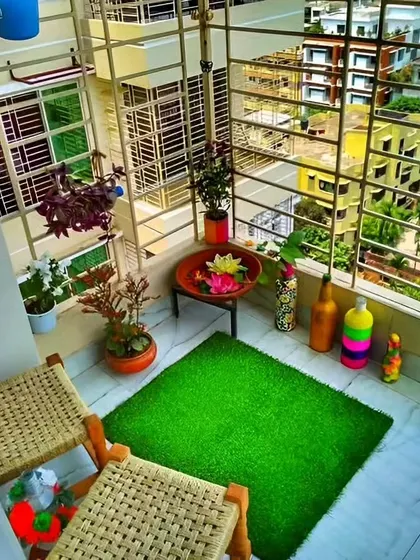 A simple yet cheerful balcony makeover. The artificial grass mat, colorful decor, and potted plants instantly brighten up this small outdoor space.