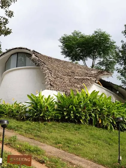 The 'Earth's Embrace' eco-retreat by Raving Dots Studio features a sculptural ferrocement shell with a thatched roof that blends organically with the hillside.
