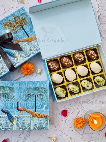 A stunning blue peacock-themed box for Diwali. Inside is an assortment of my chocolate-coated stuffed dates in different flavors like coconut, pistachio, and almond.