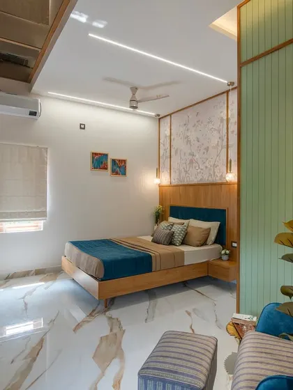 This bedroom showcases a mix of textures and colors, with a blue upholstered bed, mint green wall paneling, and a floral wallpaper accent. The design feels fresh, modern, and connected to nature.
