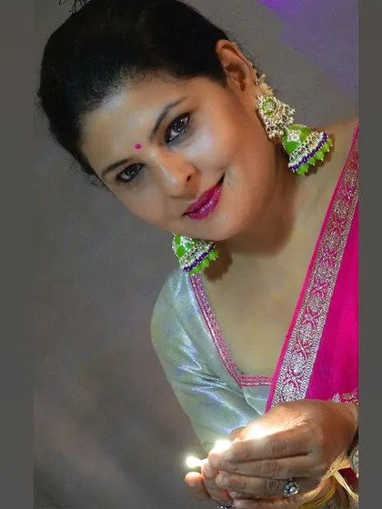 A close-up of the Diwali look, holding a diya. The focus is on the festive glow, complemented by the bright colors of the outfit and accessories.