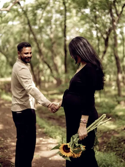 A beautiful shot of the couple in the woods. He reaches for her hand as she holds a bouquet of sunflowers, a gesture of starting their journey together.
