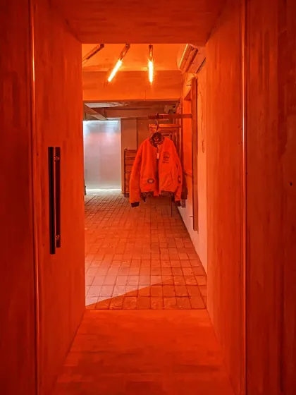 A view through the entrance corridor, bathed in a warm, rusty orange light that highlights the texture of the walls.